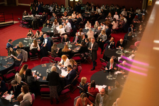 People sitting around circular tables at an awards show.