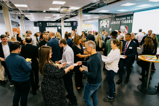 A large group of people exchanging coloured cards.